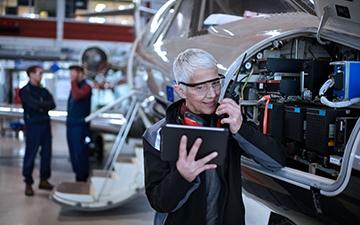 Aviation technician customer looking at iPad while working on an airplane