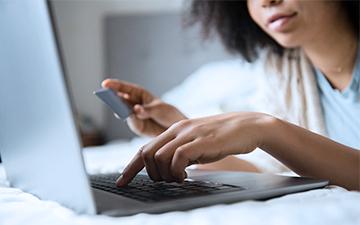 Woman holding a credit card, entering its number securely onto her laptop